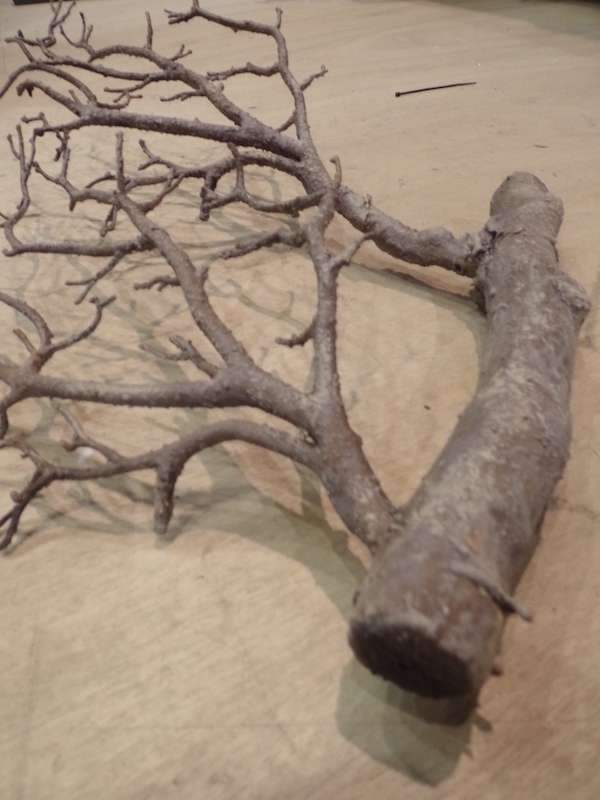 Cette branche de bois est un assemblage de morceaux factices et colorée d'une patine.